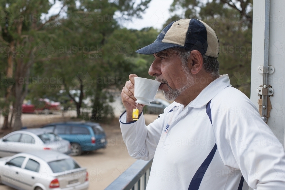 Indigenous cricketer having a cup of tea at the clubrooms - Australian Stock Image