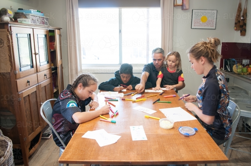 Indigenous family reading writing and drawing - Australian Stock Image