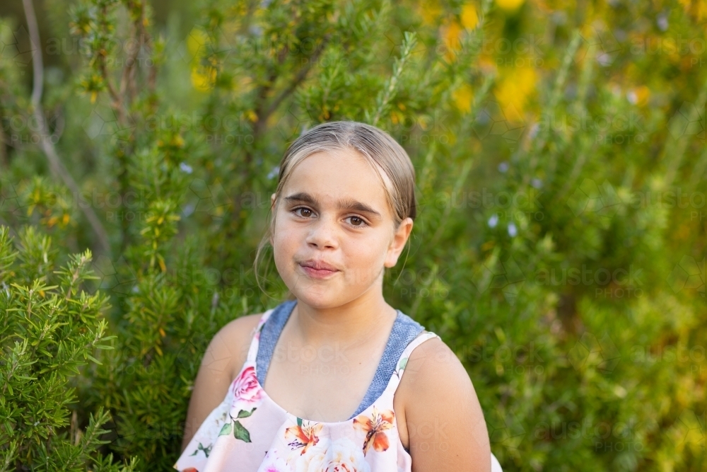 indigenous girl in front of garden greenery - Australian Stock Image