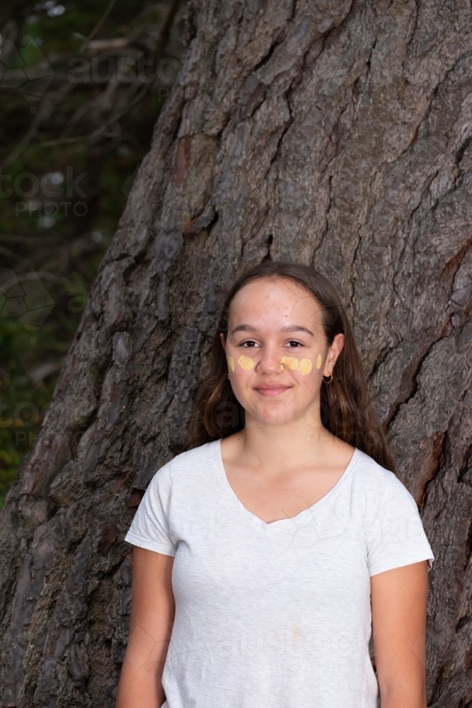 Indigenous girl near old bark tree trunk - Australian Stock Image