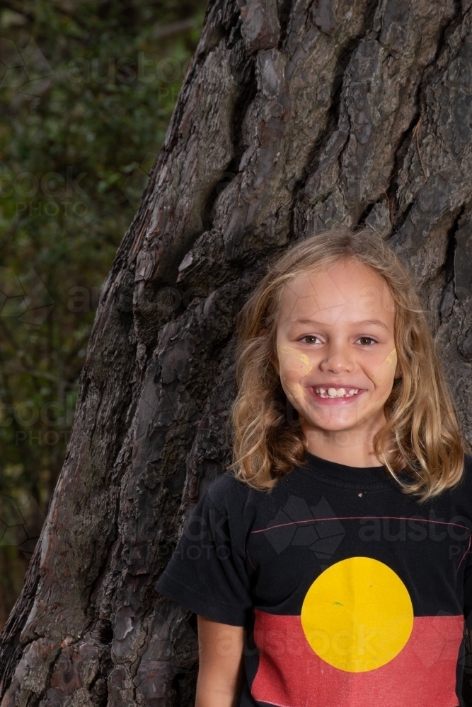 Indigenous girl near old bark tree trunk - Australian Stock Image