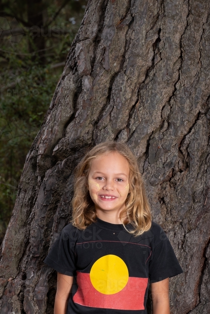 Indigenous girl near old bark tree trunk - Australian Stock Image