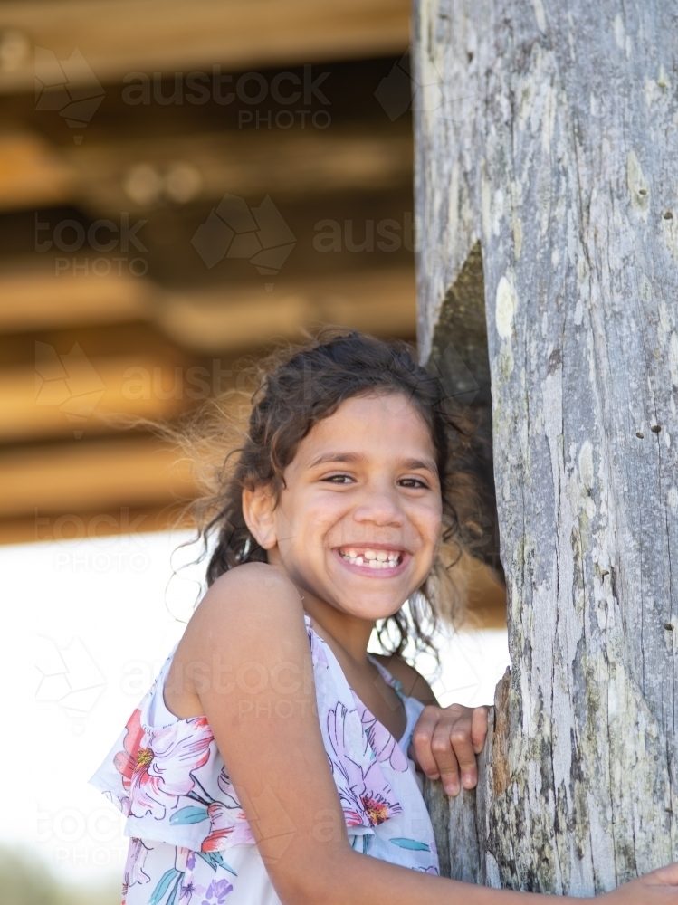 Indigenous girl standing against a wooden pole - Australian Stock Image