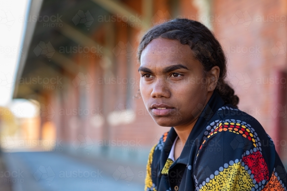 Indigenous girls staring with no emotion in front of red brick building - Australian Stock Image
