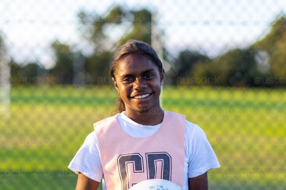 indigenous netball player in front of fence - Australian Stock Image