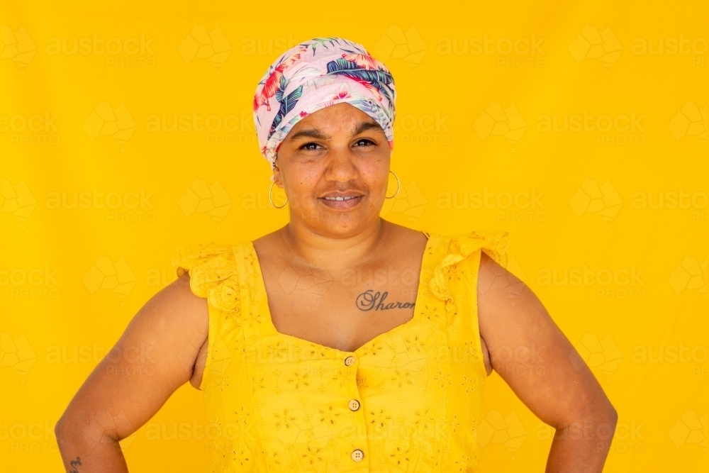 Indigenous Nyoongar woman wearing yellow against yellow backdrop - Australian Stock Image