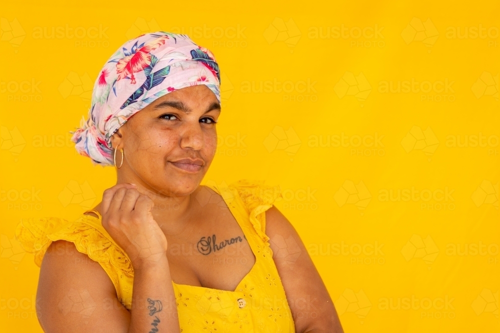 Indigenous Nyoongar woman wearing yellow against yellow backdrop - Australian Stock Image