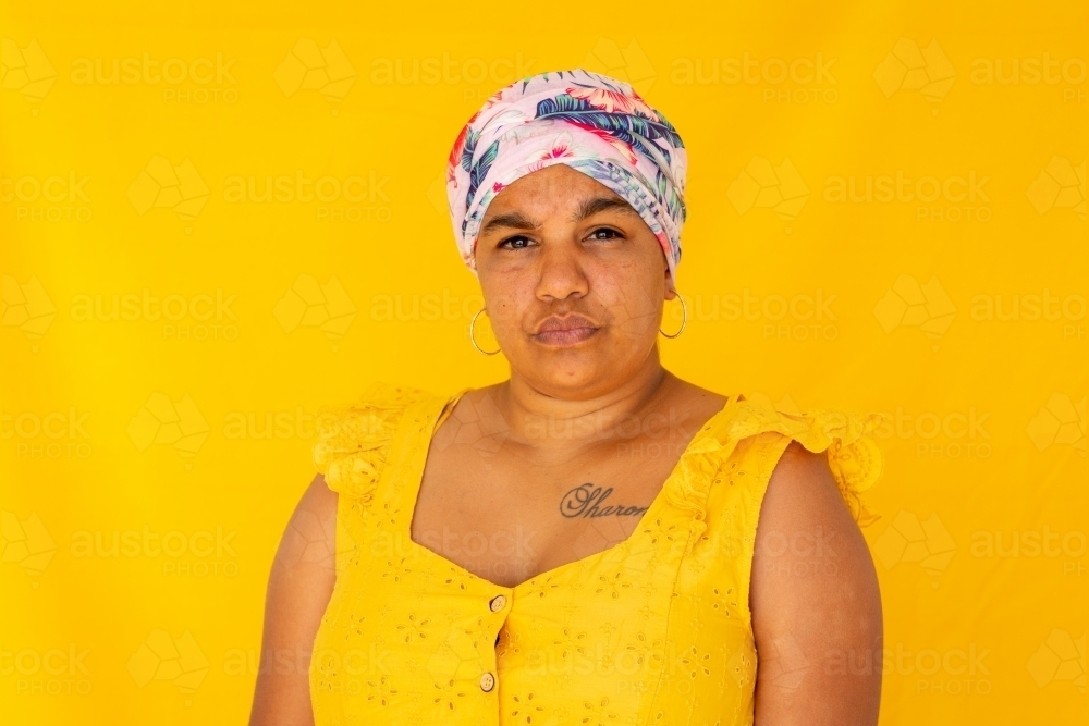 Indigenous Nyoongar woman wearing yellow against yellow backdrop - Australian Stock Image