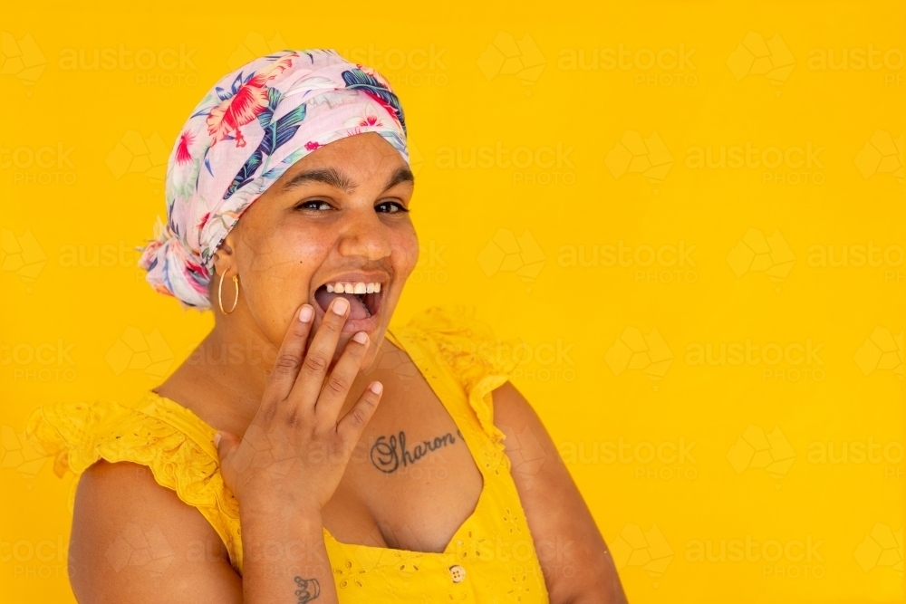 Indigenous Nyoongar woman wearing yellow against yellow backdrop - Australian Stock Image