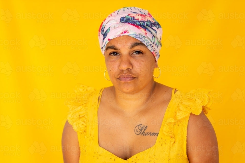 Indigenous Nyoongar woman wearing yellow against yellow backdrop - Australian Stock Image