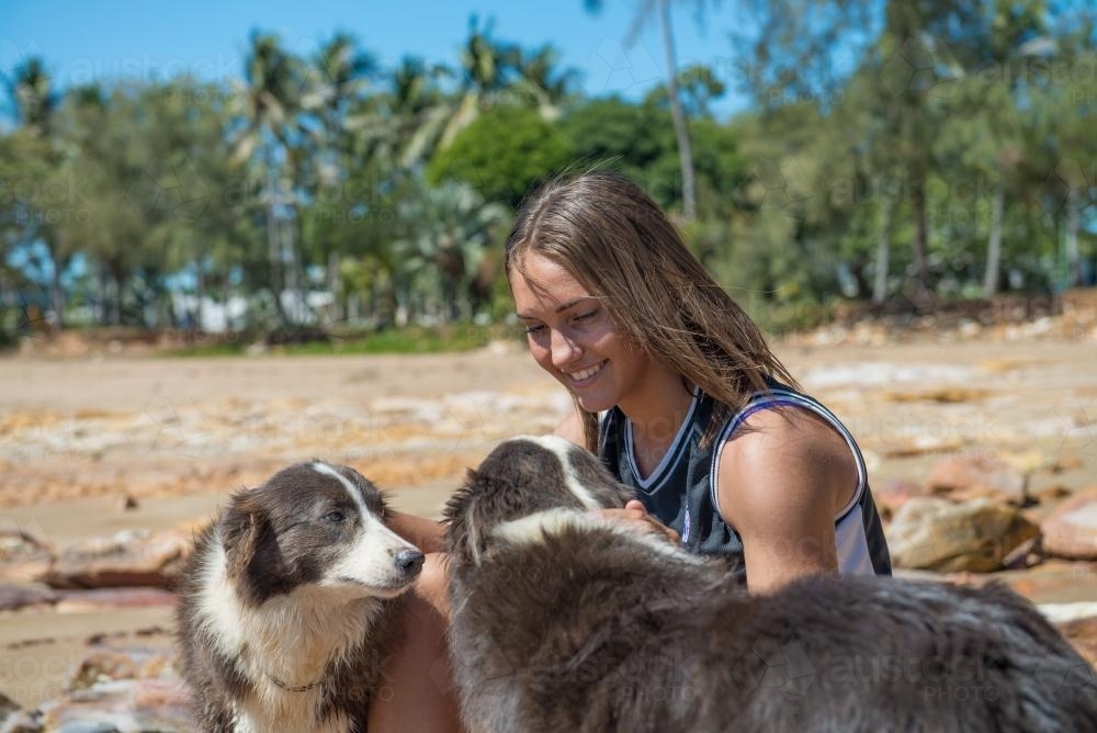 Indigenous teenager at the beach with her dogs - Australian Stock Image