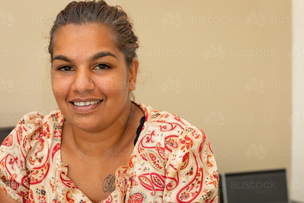 indigenous woman sitting indoors smiling - Australian Stock Image