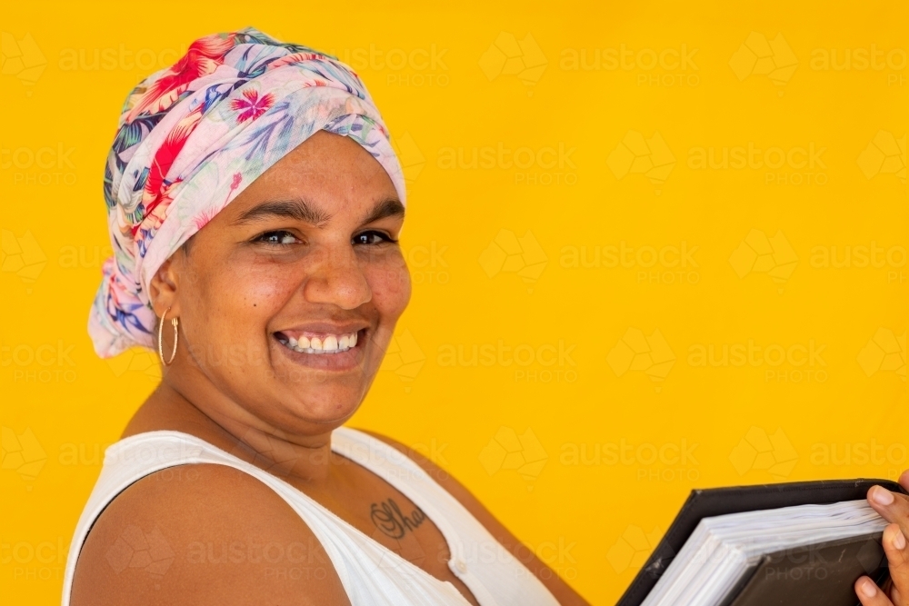 Indigenous woman wearing head wrap against a yellow background - Australian Stock Image