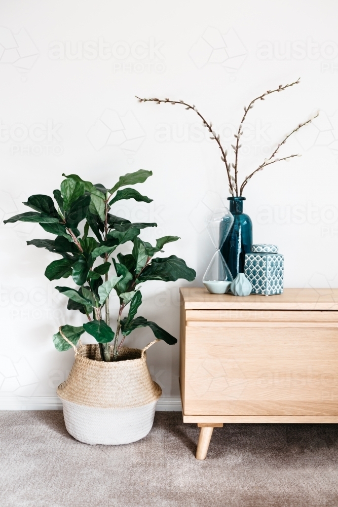 Indoor plant in a woven basket next to a buffet of vases - Australian Stock Image