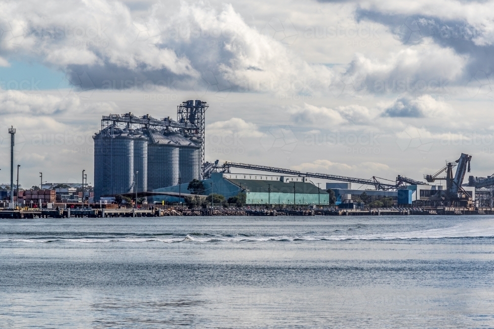Industrial buildings and loading port along coastline in harbour - Australian Stock Image