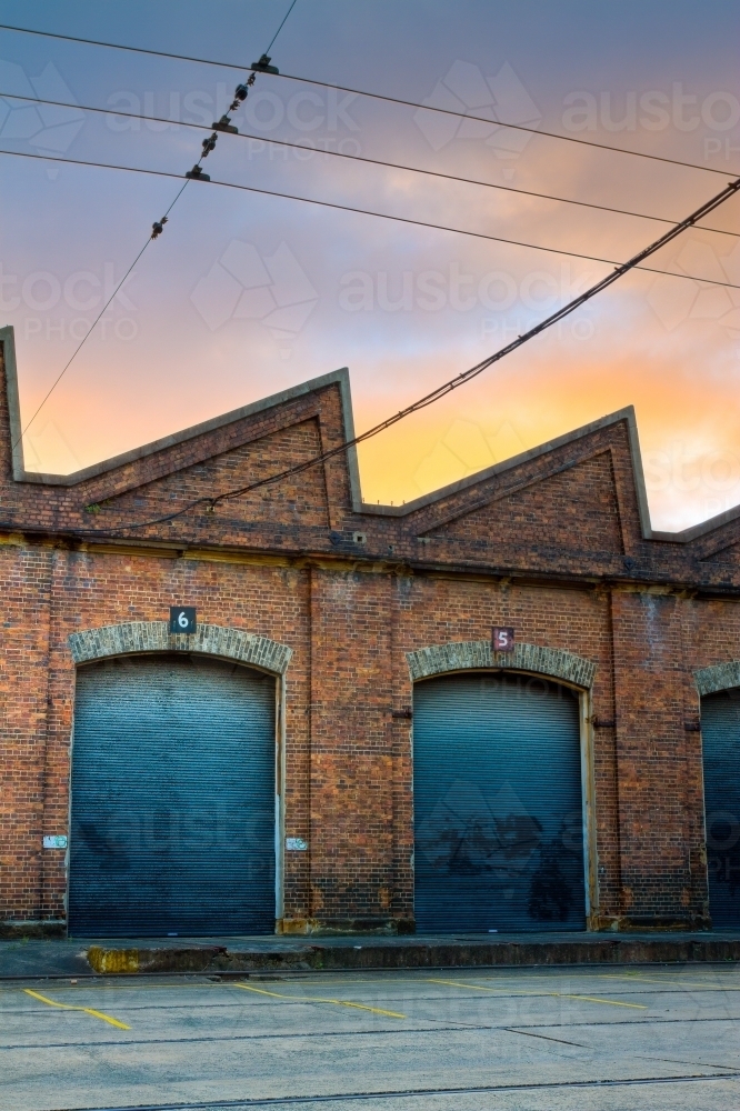 Industrial rail shed with warehouse roller doors during sunrise - Australian Stock Image