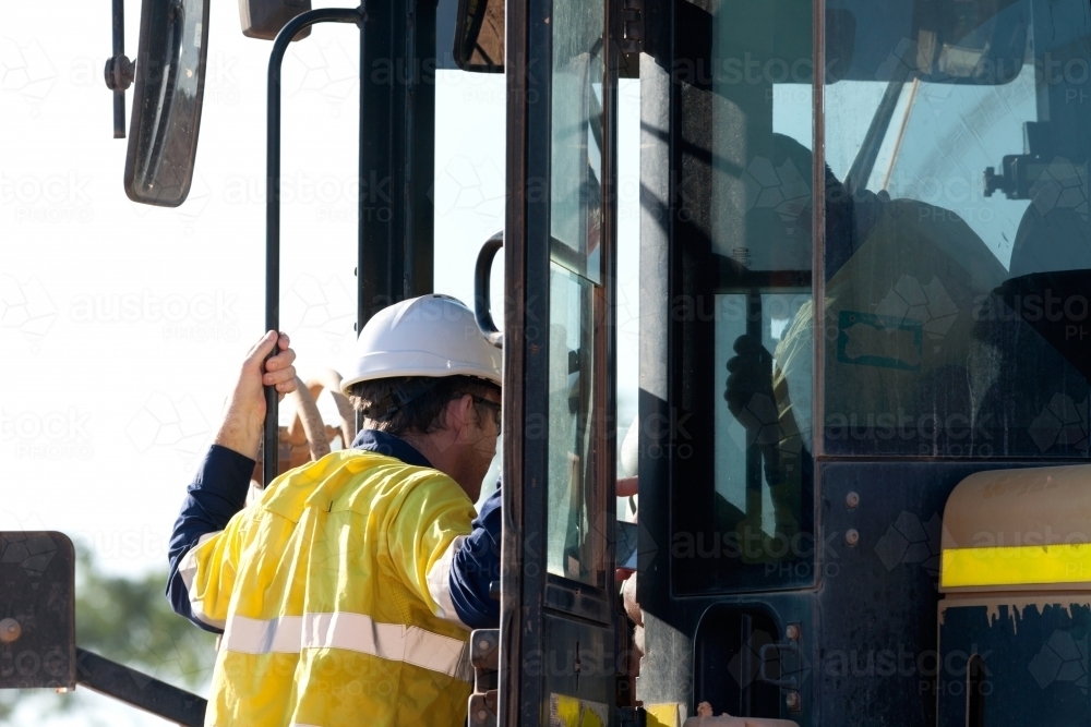 Industrial worker talking with a heavy machinery driver - Australian Stock Image