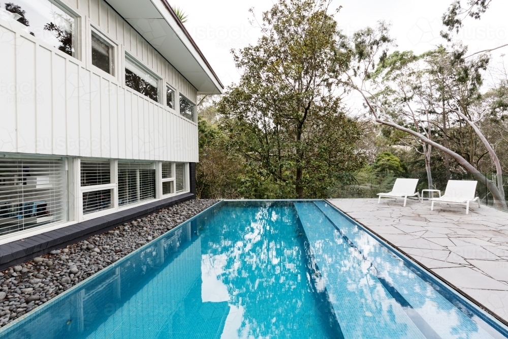 Infinity edge pool in backyard of mid century Australian luxury home - Australian Stock Image