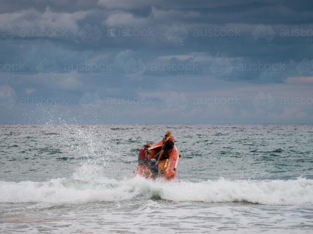 Inflatable dinghy heading out to sea through the waves - Australian Stock Image