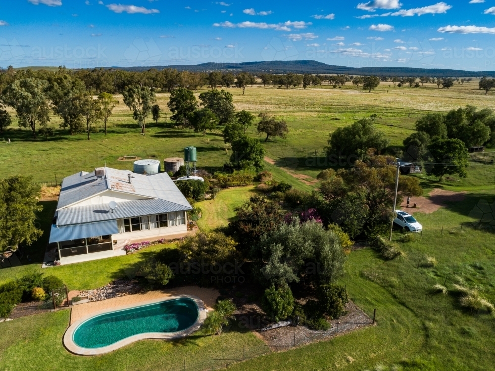 Inground swimming pool beside farm homestead house on property - Australian Stock Image
