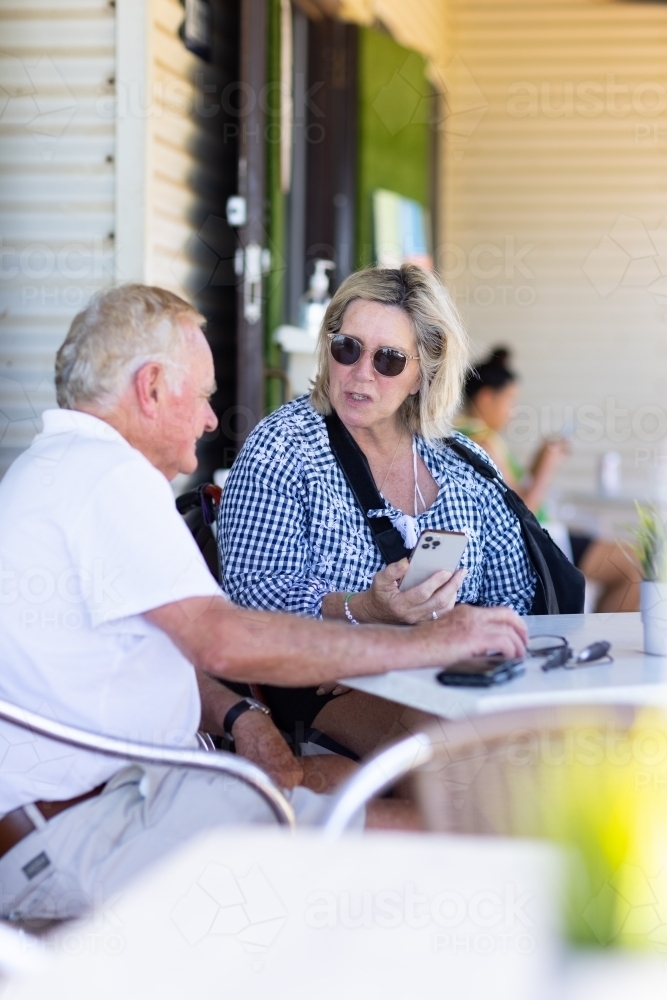 injured woman holding a smartphone talking to her husband - Australian Stock Image