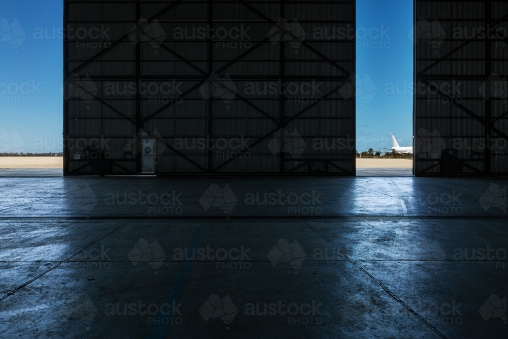 Inside an airport hangar looking out to the runway - Australian Stock Image