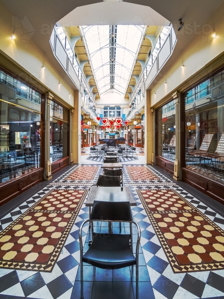 Interior of a shopping arcade with chairs and tables and decorative tile floor - Australian Stock Image