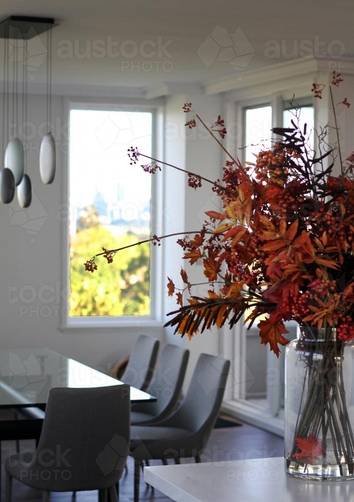Interior of modern house with vase of dried leaves in foreground - Australian Stock Image