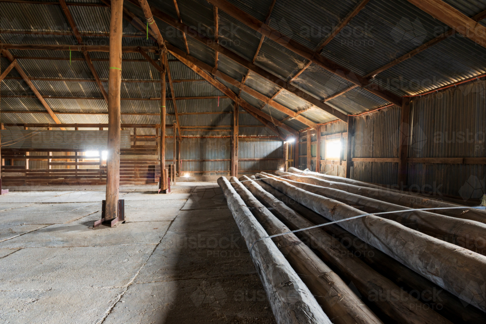 Interior of timber-framed shed with large wooden logs and corrugated walls. - Australian Stock Image