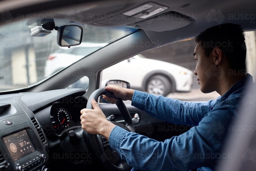 Interior shot of Asian man driving in car - Australian Stock Image