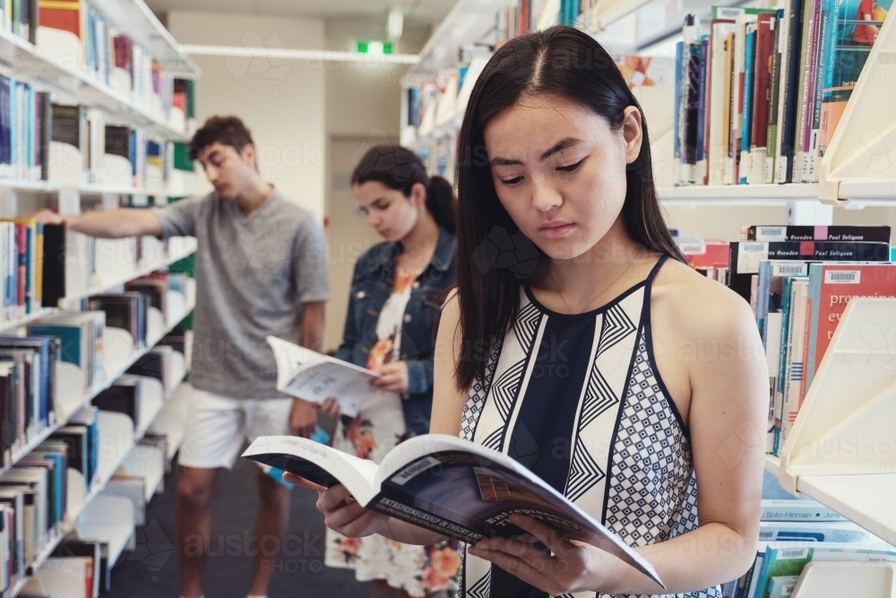 International student reading book in university library - Australian Stock Image
