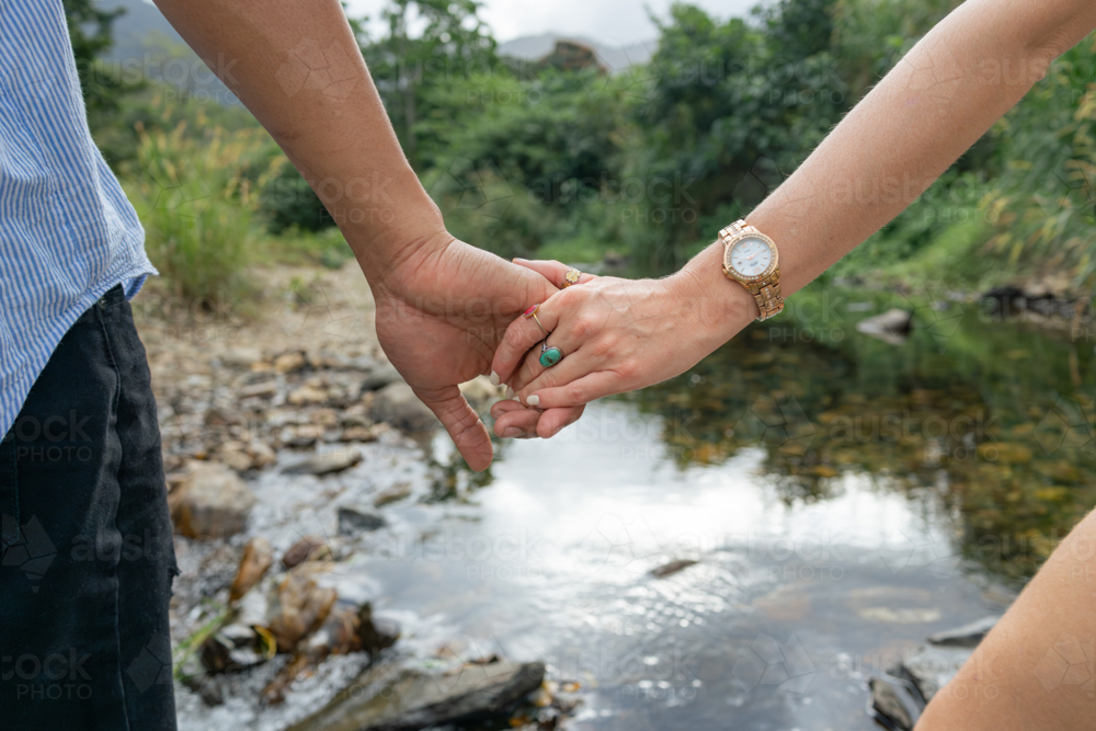 Interracial couple holding hands close-up on outdoor walk - Australian Stock Image