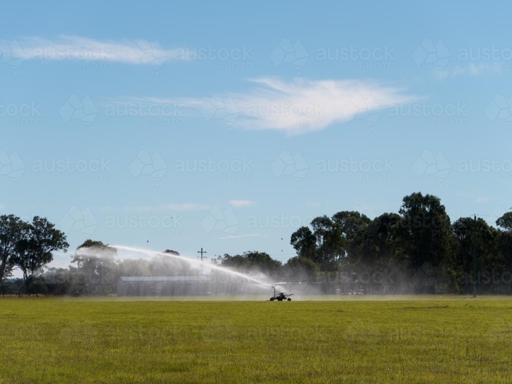 Irrigation spray shooting across a green paddock - Australian Stock Image