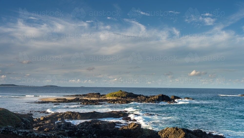 Island outcrop in ocean with windy clouds - Australian Stock Image
