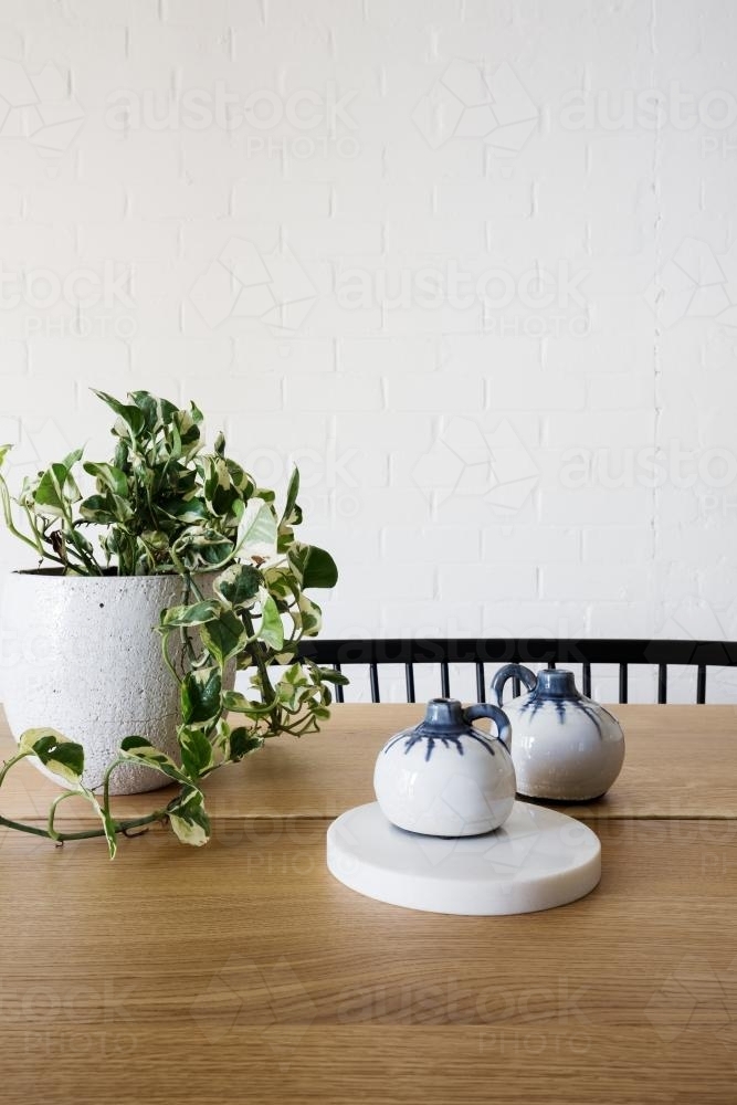 Ivy pot plant on table and white brick wall in dining room vertical - Australian Stock Image