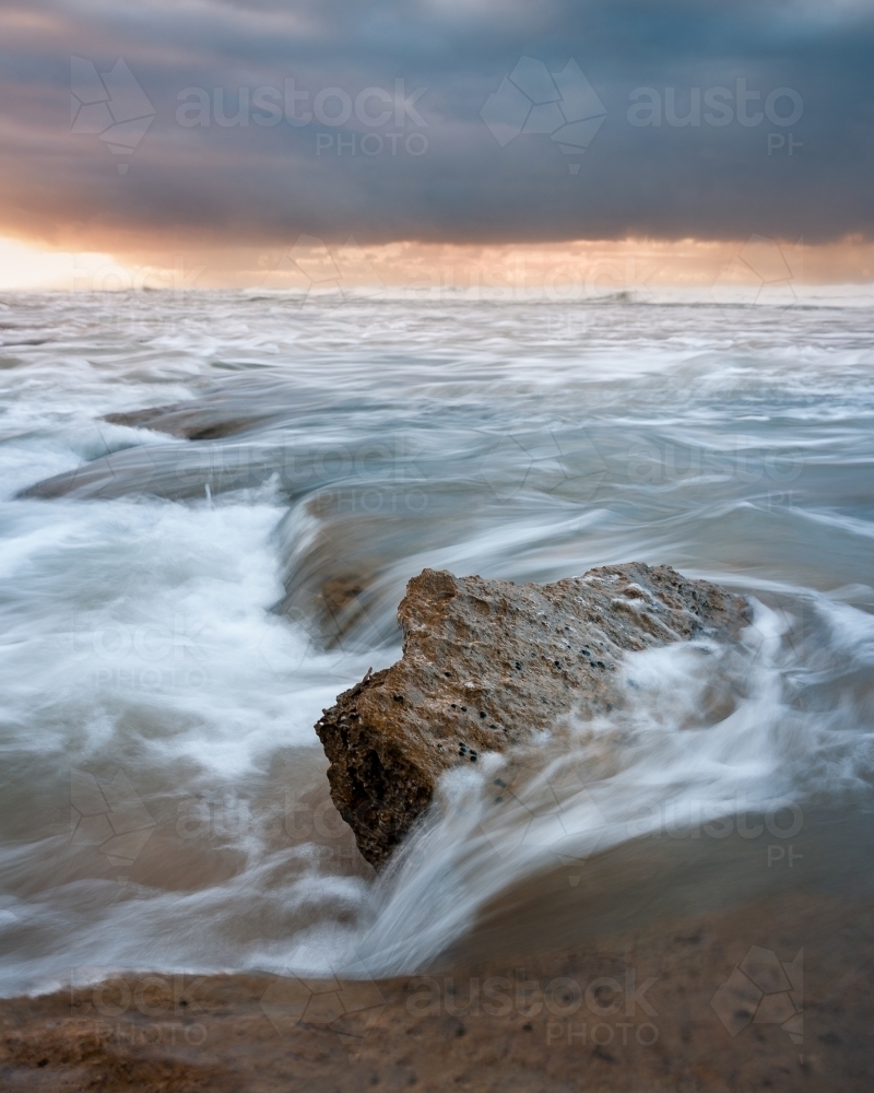 Jagged Rock Surrounded by Crashing Waves at Sunrise - Australian Stock Image