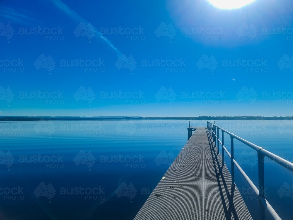 Jetty on Tuggerah Lake on the NSW Central Coast on clear sunny day with blue sky - Australian Stock Image