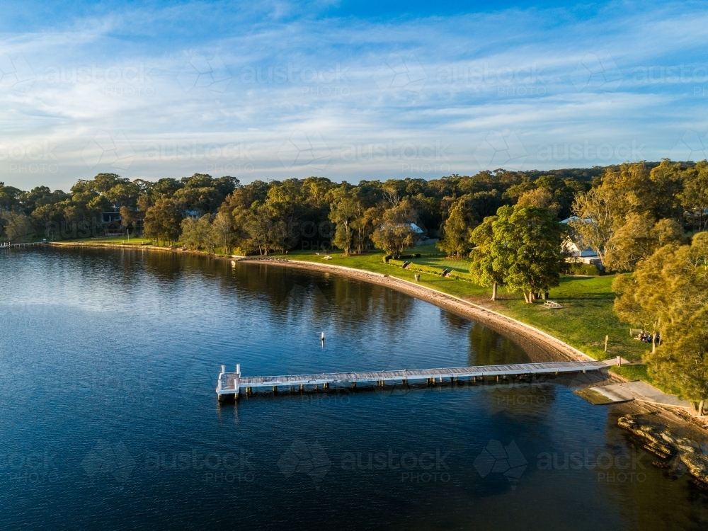 Jetty out in water of Lake in sunset light - Australian Stock Image