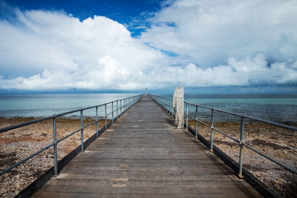 jetty over rocky beach with cloudy skies - Australian Stock Image
