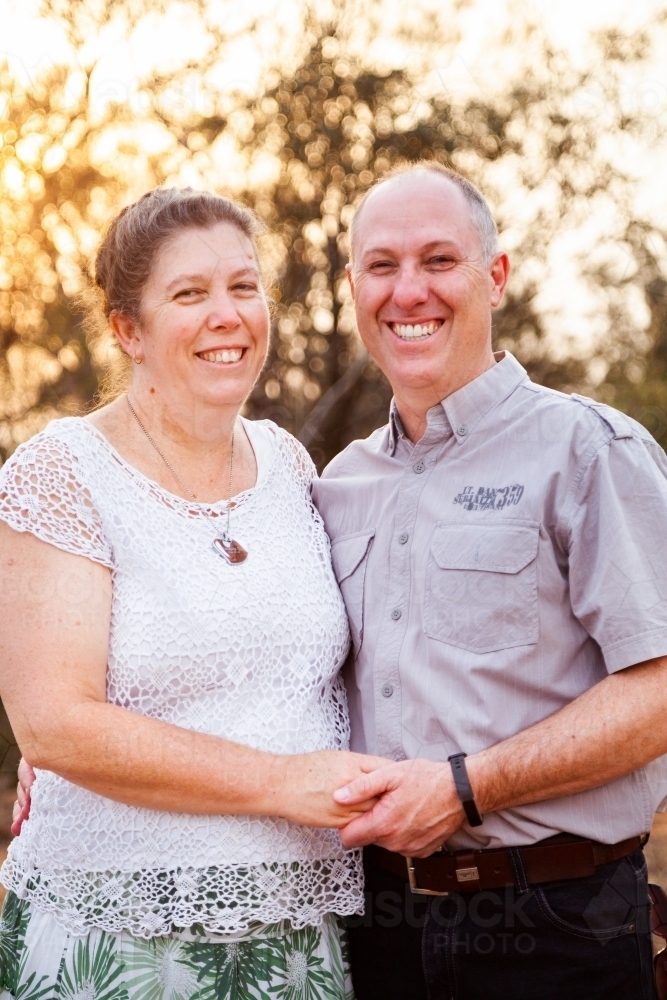 Joyful middle aged couple standing together in afternoon light - faithfulness - Australian Stock Image