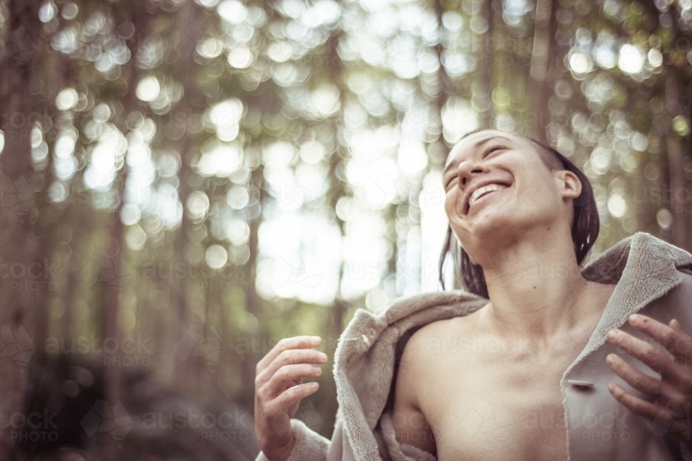 Joyful woman with jacket open laughing and dancing in the bush - Australian Stock Image