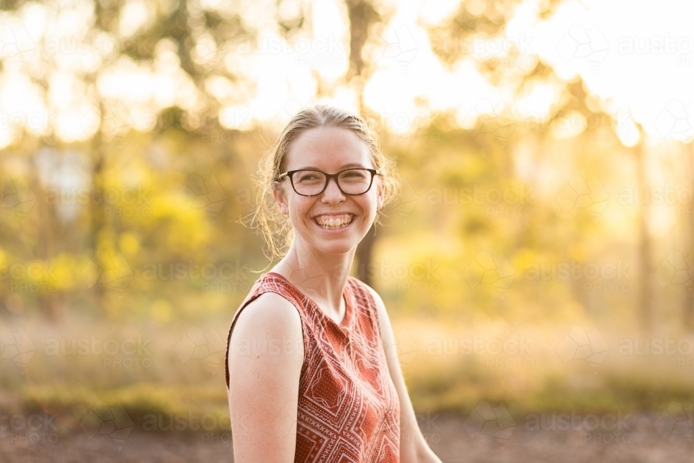Joyful young person laughing in golden light outside - Australian Stock Image