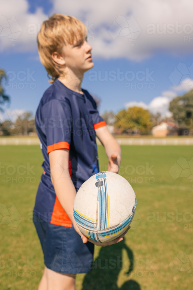Junior rugby union player on field handling ball - Australian Stock Image