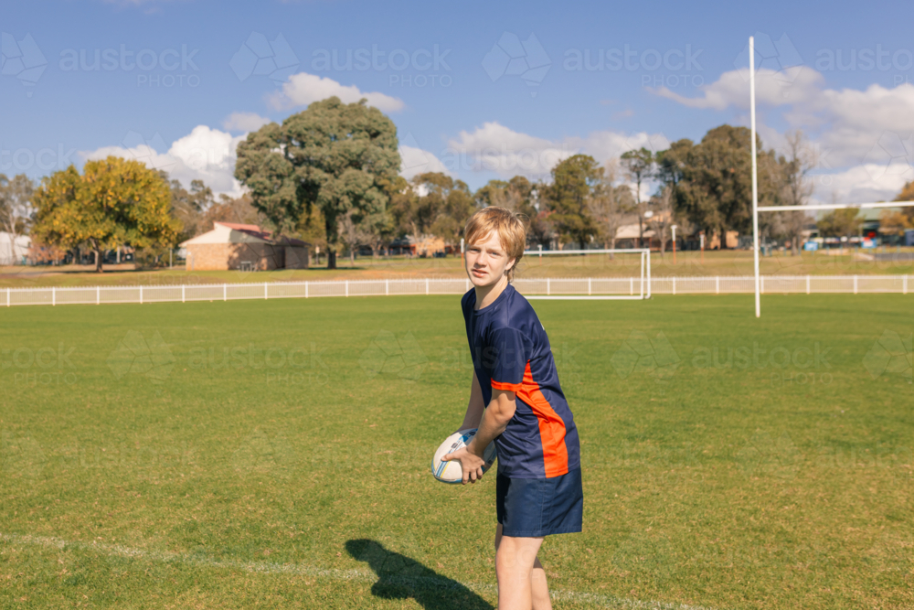 Junior rugby union player practicing ball pass on field - Australian Stock Image