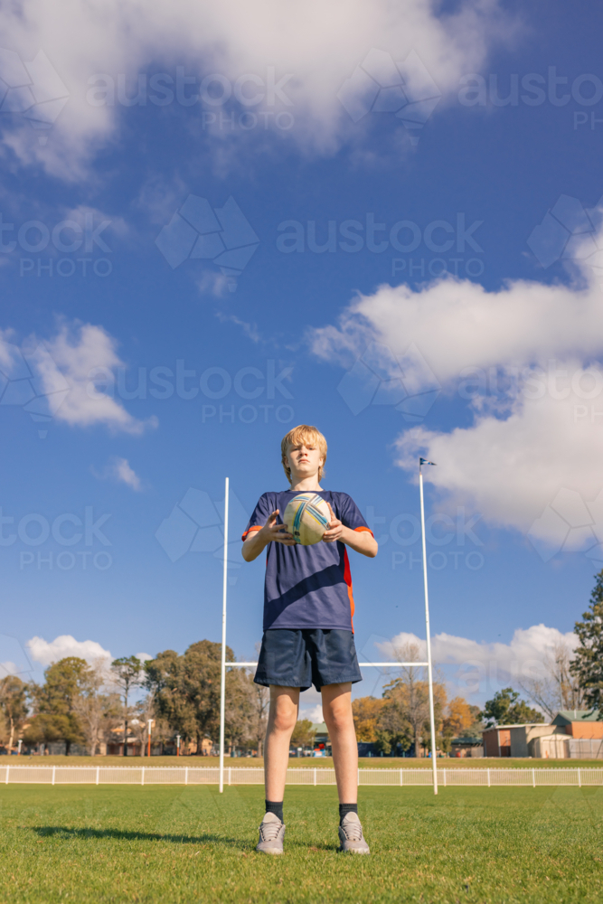 Image of Junior rugby union player standing on field holding ball with ...