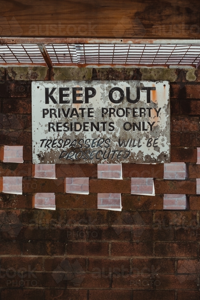 Keep out, private property sign on an old brick wall in a car port. - Australian Stock Image