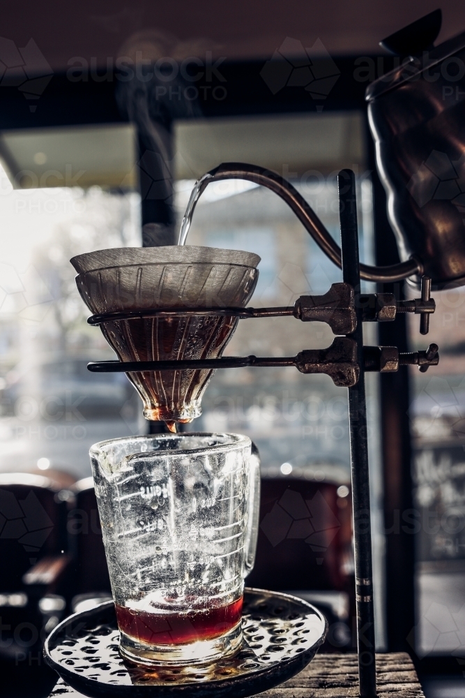 Kettle pouring hot water into V60 coffee filter in the sunlight - Australian Stock Image