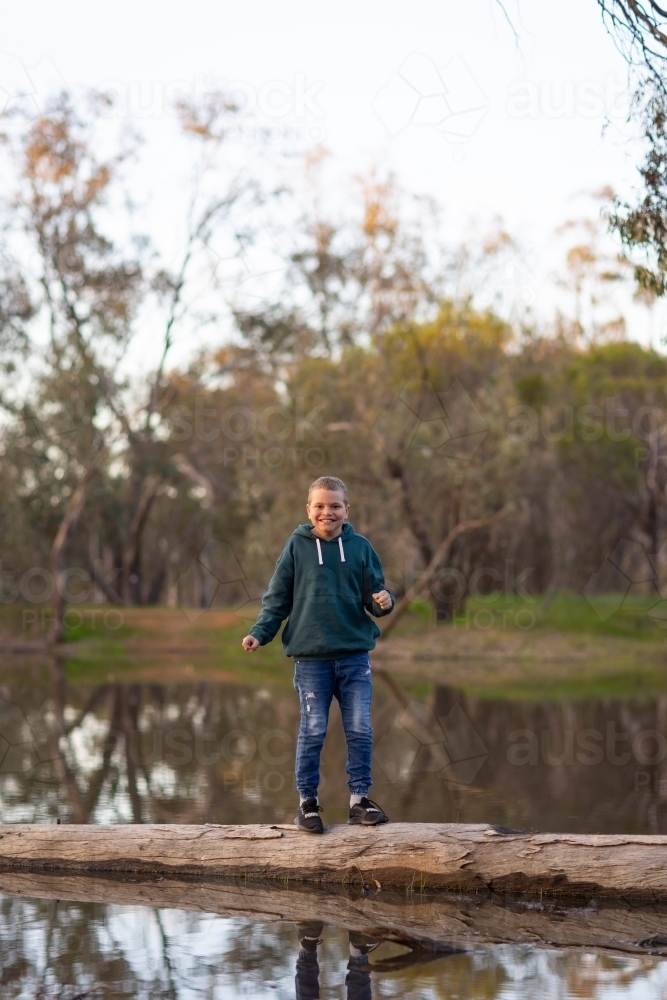 kid balancing on log in water - Australian Stock Image