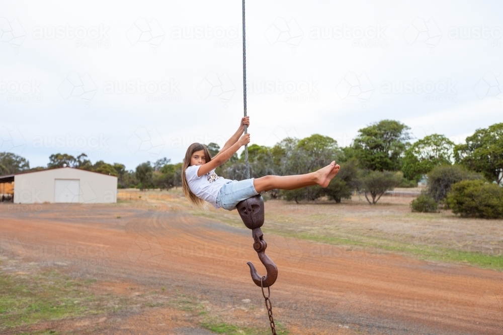 Kid climbing on old crane hook cable - Australian Stock Image
