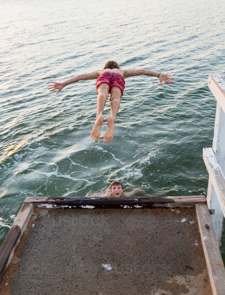 Kid diving off jetty into a lake - Australian Stock Image